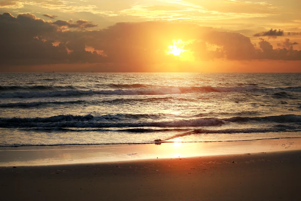 Golden sunrise over gentle surf on a quiet sandy beach